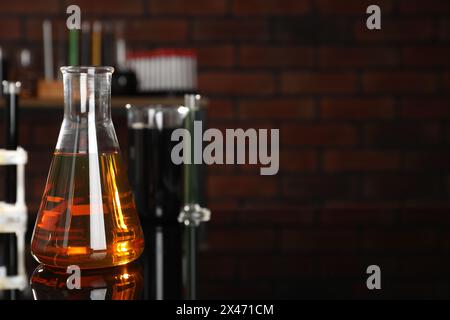 Laborglas mit verschiedenen Ölsorten auf schwarzem Spiegeltisch im Innenbereich, Nahaufnahme. Leerzeichen für Text Stockfoto