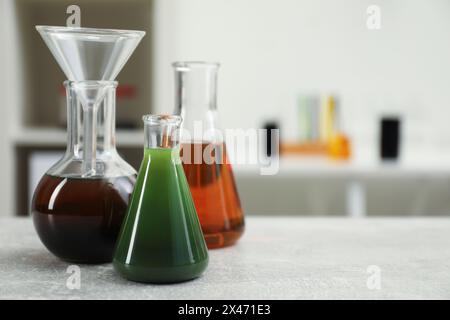 Laborglas mit verschiedenen Rohölsorten auf hellgrauem Tisch, Platz für Text Stockfoto