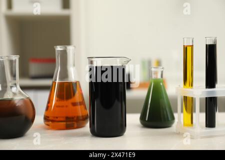 Laborglas mit verschiedenen Rohölsorten auf einem hellen Marmortisch Stockfoto