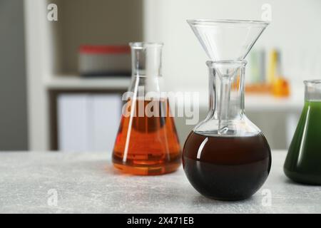 Laborglas mit verschiedenen Rohölsorten auf hellgrauem Tisch, Platz für Text Stockfoto