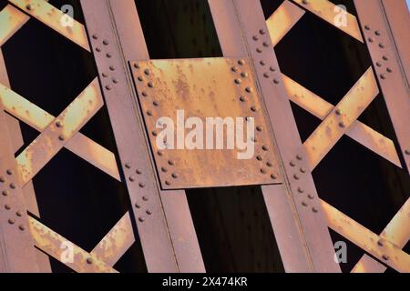 Nahaufnahme einer alten verrosteten Struktur aus Platten und genieteten Gelenken. Stahl aus Nickellegierung für den Brückenbau. Stockfoto