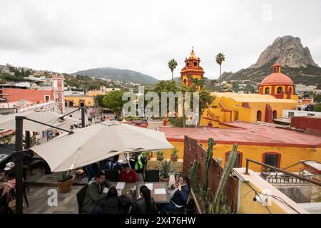 Bernal, Querétaro, Mexiko - 20. November 2023: Ein Restaurant und die historische Kirche in der Innenstadt strahlen in einem bewölkten Morgenlicht. Stockfoto