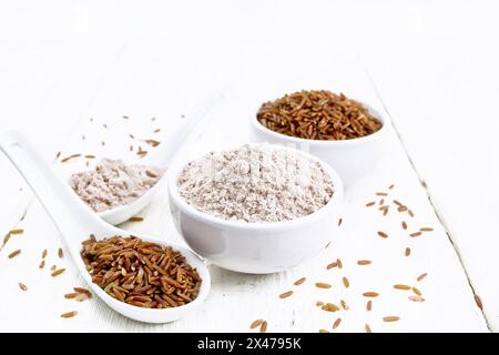 Rotes Reismehl in Schüssel und Löffel, Müsli im Löffel, Schüssel auf Holzbrett Hintergrund Stockfoto