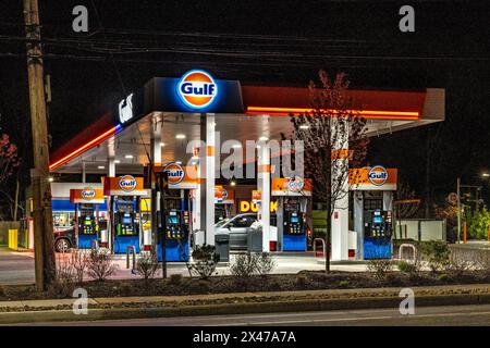 Suffern, NY - USA - 20. April 2024 Abendblick auf die belebte Airmont Gulf Tankstelle. Die Neonlichter beleuchten die Gegend und werfen einen Schein über den Stockfoto
