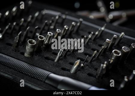 Schraubendreher-Kit mit Aluminium-Bitdreher auf schwarzem Tablett. Treibergriff mit magnetischer Bit-Buchse und Rändelgriff. Stockfoto