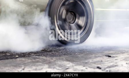 Ziehen Sie den brennenden Reifen des Rennwagens an der Startlinie auf der Rennstrecke Stockfoto