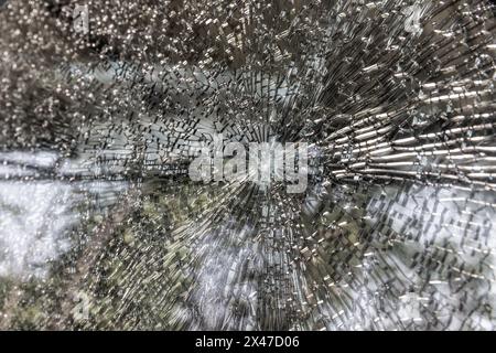 Gebrochene Windschutzscheibe eines Autos, Nahaufnahme als Hintergrund. Glasbruch mit Rissen. Stockfoto