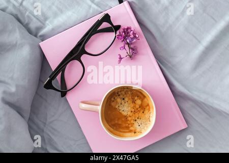 Komposition mit rosa Becher mit Kaffee, rosa Notizblock oder Tagebuch und Gläsern auf dem Bett, Blick von oben Stockfoto