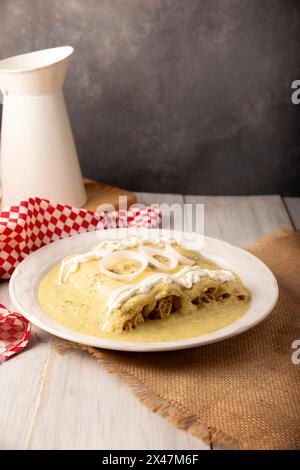 Mexikanisches Essen. Enchiladas mit cremiger grüner Sauce gefüllt mit gehacktem Hühnerfleisch und mit geschmolzenem Käse bedeckt, in Mexiko werden sie Swiss Enc genannt Stockfoto