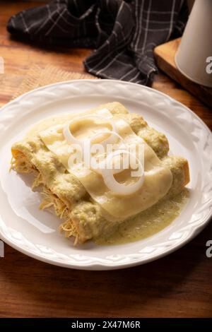 Mexikanisches Essen. Enchiladas mit cremiger grüner Sauce gefüllt mit gehacktem Hühnerfleisch und mit geschmolzenem Käse bedeckt, in Mexiko werden sie Swiss Enc genannt Stockfoto