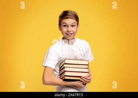 Teen Junge lächelnd mit Haufen von Büchern in den Händen Stockfoto