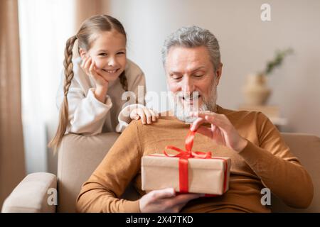 Ein älterer Mann und ein junges Mädchen, das Geschenk hält Stockfoto