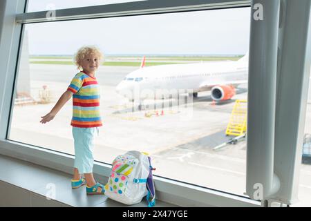 Kinder am Flughafen. Kinder schauen auf das Flugzeug. Reisen und Fliegen mit Kind. Familie am Abflugsteig. Urlaub und Reisen mit kleinen Kindern. Stockfoto