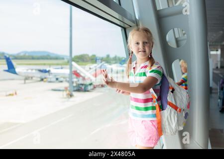 Kinder am Flughafen. Kinder schauen auf das Flugzeug. Reisen und Fliegen mit Kind. Familie am Abflugsteig. Urlaub und Reisen mit kleinen Kindern. Stockfoto