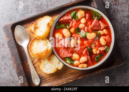 Crockpot-Eintopf mit Chorizo, Butterbohnen und Spinat in einer Schüssel, serviert mit geröstetem Brot auf dem Tisch. Horizontale Draufsicht von oben Stockfoto