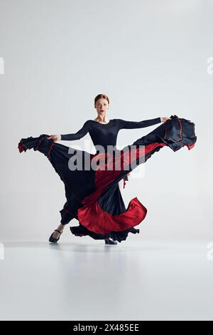 Leidenschaftlicher Flamenco-Tanz. Künstlerische Frau mit dynamischem Posentanz vor grauem Studiohintergrund Stockfoto