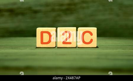 Konzept von D2C (direkt an den Kunden), Wort D2C auf Holzwürfeln auf grünem gesättigtem Hintergrund Stockfoto