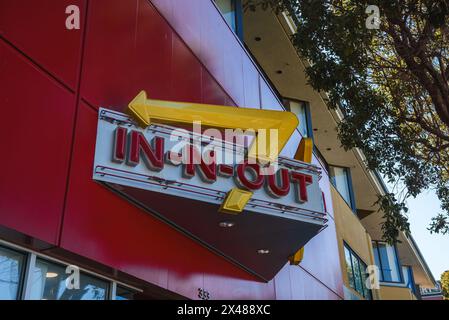 Legendäres in N Out Burger-Schild, gelber Pfeil und Name vor der roten Wand in kalifornischem Stadtbild. Stockfoto