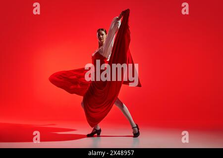 Künstlerische Flamenco-Tänzerin mit Leidenschaft vor auffälligem rotem Hintergrund. Elegante Pose und fließender Rock zeigen intensive Tanzgefühle. Stockfoto