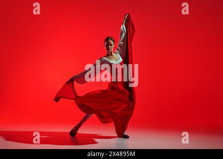 Künstlerische Flamenco-Tänzerin mit Leidenschaft vor auffälligem rotem Hintergrund. Elegante Pose und fließender Rock zeigen intensive Tanzgefühle. Stockfoto