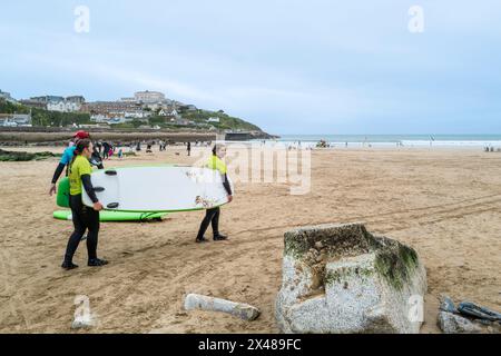 Ein Surflehrer der Escape Surf School mit Surfern am Towan Beach in Newquay in Cornwall, Großbritannien. Stockfoto