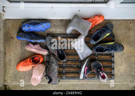 Eine Auswahl an Kinderschuhen liegt auf einer vorderen Türstufe. Stockfoto