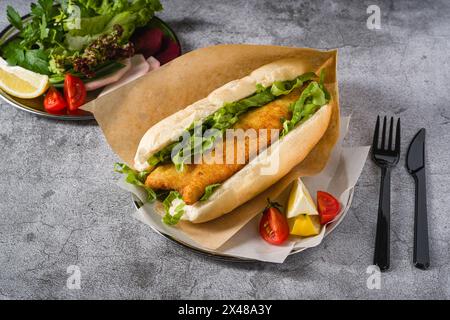 Gebratenes Fisch-Sandwich mit Gemüse auf dem Steintisch. Türkischer Name Balik Ekmek Stockfoto