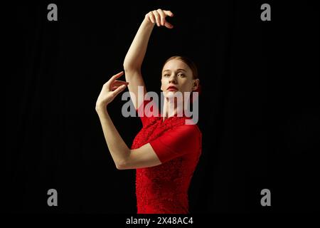 Kreatives Porträt einer eleganten Frau in rotem Kleid, Flamenco-Tanz, der vor schwarzem Hintergrund posiert Stockfoto