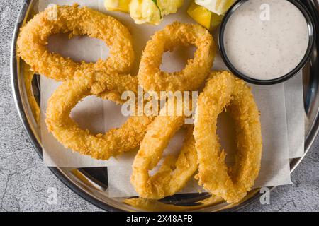 Gebratene Calamari mit Kartoffelsalat daneben auf Steintisch Stockfoto