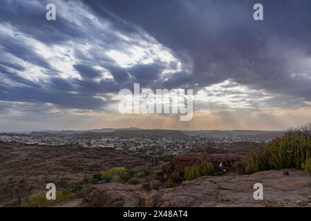 Blick auf die Stadt mit dramatischen Sonnenstrahlen orange Himmel am Abend vom Gipfel des Berges wird in mehrangarh Fort jodhpur rajasthan indien aufgenommen. Stockfoto