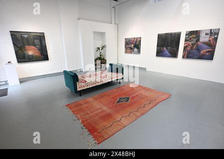 Elizabeth Xi Bauer Gallery, Deptford, London, Großbritannien. Mai 2024. Die Einzelausstellung „gefangen in the Act of Being Own“ von Alexandra Zarins zeigt Zarins' sich weiterentwickelnde Erforschung von Konzepten wie Intimität, soziale Interaktionen, persönliche Nähe und emotionale Turbulenzen. Ein Sofa und Teppich fügen eine Wohnsituation hinzu, die Besucher beim Betrachten der Werke nutzen können. Quelle: Malcolm Park/Alamy Live News Stockfoto