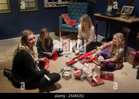 Mutter und Töchter verpacken Geschenke im Haus der Familie Dorset in Christmas, England, Großbritannien Stockfoto