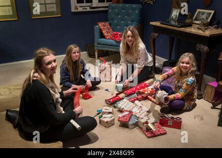 Mutter und Töchter verpacken Geschenke im Haus der Familie Dorset in Christmas, England, Großbritannien Stockfoto