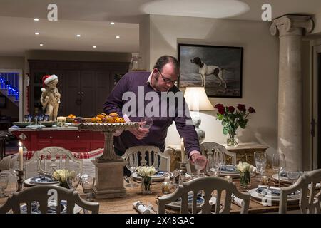 Ein Mann, der einen Tisch im Haus der Familie Dorset zu Weihnachten legt, England, Großbritannien Stockfoto