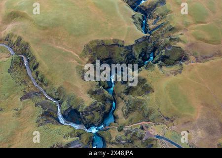 Zwischen den Hügeln Islands fließt der sich windende blaue Fluss, ein Ast von Gebirgsbächen. Blick von der Drohne Stockfoto