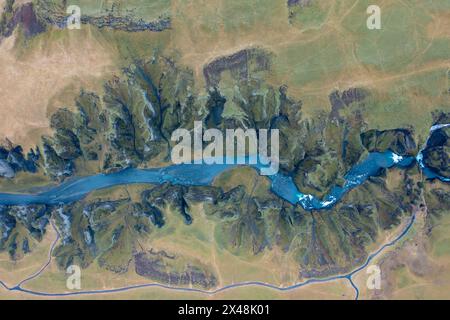 Gewundenes blaues Flussbett, das zwischen Felsen in Island fließt, natürliche atemberaubende Landschaft. Drohnenaufnahme Stockfoto