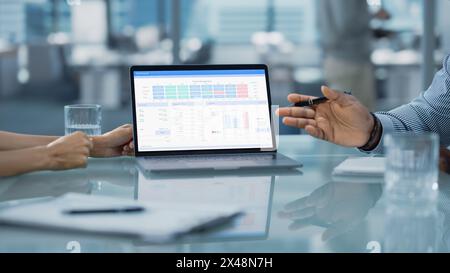 Nahaufnahme eines Computerbildschirms. Besprechungsraum im Büro: Team aus zwei kreativen Unternehmern diskutiert Finanzdaten und Wachstumsstrategie. Stilvolle Geschäftsleute arbeiten an der Investition in Immobilien. Stockfoto