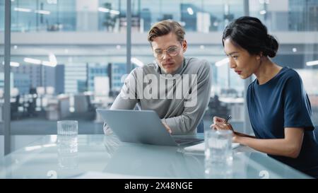 Konferenz im Konferenzraum „Multiethnische Vielfalt“: Team aus zwei kreativen Unternehmern spricht, diskutiert Wachstumsstrategie. Stilvolle junge Geschäftsleute arbeiten an Investitions- und Marketingprojekten. Stockfoto