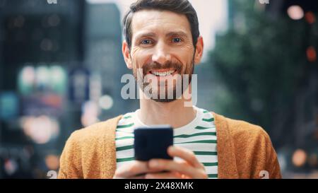 Kaukasier benutzt Smartphone in der Großstadt. Kreativer Profi mit Mobile Phone App für E-Commerce-Investitionen, Online-Shopping, soziale Medien und Surfen im Internet. Porträt Aufgenommen. Stockfoto