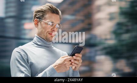 3Street Shot: Gutaussehender Kaukasier mit Smartphone in der Big City. Kreativexperte mit Mobile Phone App für E-Commerce-Investitionen und Online-Shopping. Bewegungshintergrund Unschärfen. Stockfoto