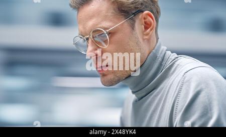 Modernes Büro Close-up Porträt: Schöner Geschäftsmann, der an seinem Schreibtisch sitzt und am Computer arbeitet. Professioneller Digitaler Unternehmer Lächelnd. Unscharfer Bewegungshintergrund. Stockfoto