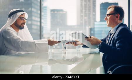Zwei erfolgreiche multikulturelle Geschäftsleute sitzen im Amt und unterzeichnen den Vertrag. Arabischer Geschäftspartner mit Investor macht lukratives Finanzgeschäft. Saudi, Emirat, Arabisches Geschäftsmann-Konzept. Stockfoto