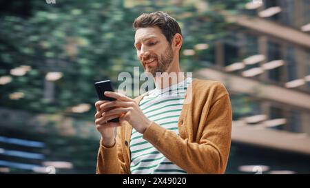 Straßenaufnahme: Porträt eines Kaukasiers mit Smartphone in der Großstadt. Creative Professional mit der Mobile Phone App für E-Commerce Online-Shopping. Unscharfer Hintergrund. Stockfoto