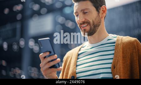 Kaukasier benutzt Smartphone in der Großstadt. Kreativer Profi mit Mobile Phone App für E-Commerce-Investitionen, Online-Shopping, soziale Medien und Surfen im Internet. Porträt Aufgenommen. Stockfoto