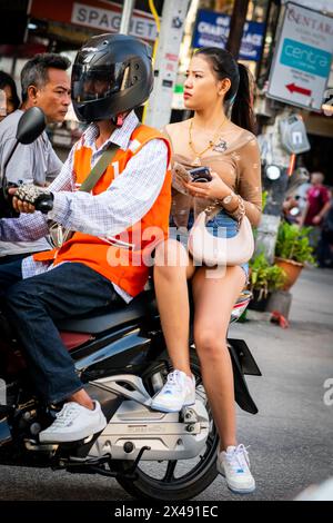 Eine attraktive Thai-Frau fährt auf der Rückseite eines Motorradtaxis. Diese Aufnahme wird an der geschäftigen Kreuzung von Soi Buakhao und Soi Lengkee aufgenommen. Pattaya. Stockfoto