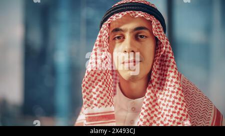 Porträt eines erfolgreichen muslimischen Geschäftsmannes im traditionellen Outfit, der für die Kamera posiert, sanft lächelnd. Saudi, Emirat, Arabisches Geschäftsmann-Konzept. Stockfoto
