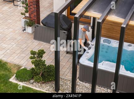 Professioneller Caucasian Garden SPA-Techniker, der die Installation des Wannen-Whirlpools beendet Stockfoto