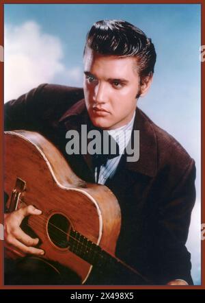 Elvis Presley ikonischer amerikanischer Popstar-Sänger und Filmschauspieler posiert mit seiner Gitarre 1950er Vintage-Werbestudio Portrait mit blauem Himmel Hintergrund Hollywood USA Stockfoto