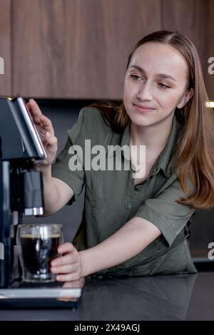 Frau, die einen frischen Kaffee mit einer Kaffeemaschine zubereitet. Kaffeemischer und Haushaltsgeräte für die Zubereitung von Heißgetränken. Stockfoto