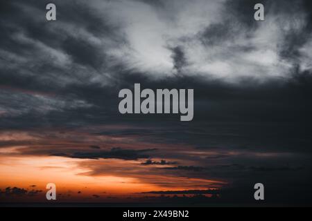 Dramatische und stimmungsvolle Wolken am Himmel. Farbkontrast von tiefen Grautönen bis zu warmen Orangen. Stockfoto